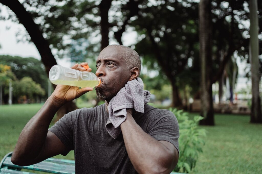 man in black crew neck t shirt drinking yellow liquid from plastic bottle